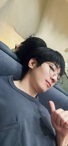 a woman with black hair and glasses sitting on a couch