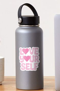 a water bottle with the words love your self printed on it next to other items