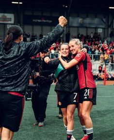 two female soccer players hugging each other on the field