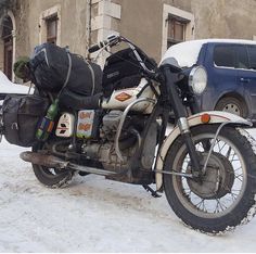 a motorcycle parked in the snow next to a car