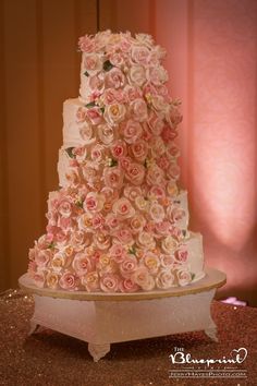 a three tiered wedding cake covered in pink flowers