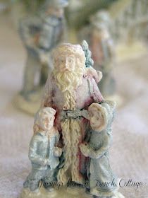 small figurines of santa claus and two other figures on a tableclothed surface