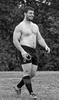 a man without a shirt holding a frisbee in his hand while standing on the grass