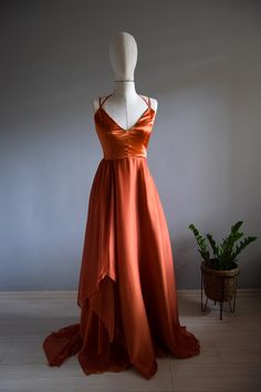 an orange dress is on display in front of a plant