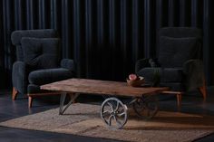 a living room with two chairs and a coffee table in front of a black curtain