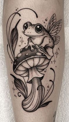 a black and white tattoo with a frog on it's leg, holding a mushroom