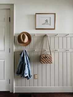 a hat, coat rack and purse hanging on the wall in front of a door