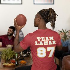 a man with dreadlocks holding a basketball in front of his face while sitting on a couch