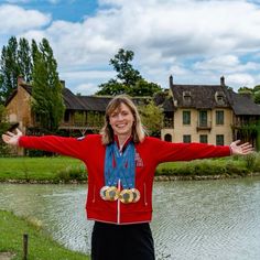 a woman standing in front of a lake with her arms spread out to the side