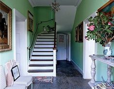 the hallway is decorated in green and white with stairs leading up to the second floor