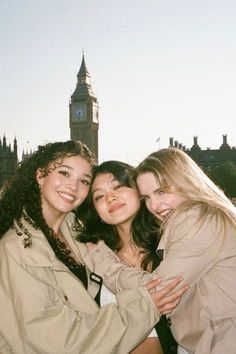 three girls are posing in front of the big ben clock tower, with their arms around each other