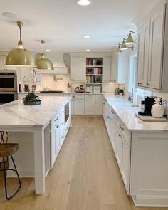 a large kitchen with white cabinets and wood flooring, along with an island in the middle