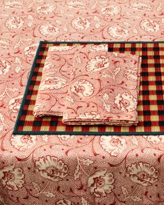 three pieces of red and black fabric on a table cloth with floral designs in the center