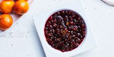 a white bowl filled with cranberry sauce next to oranges on a table