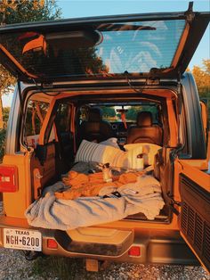 an orange van with the back door open filled with blankets and pillows