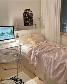 a bedroom with a bed, desk and computer monitor on the table in front of it