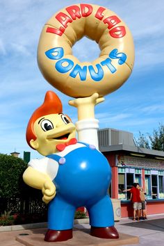 the giant donut statue is in front of a building with an advertisement on it