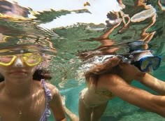 two women wearing goggles and snorkels are swimming in the clear water