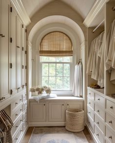 an arched window in the corner of a walk - in closet with white cabinets and drawers