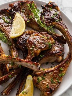 steaks with lemon wedges and herbs on a white plate