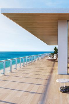 an outdoor deck with chairs and tables overlooking the ocean