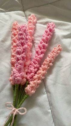 pink crocheted flowers tied together on a bed