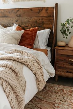 a bed with pillows and blankets on top of it next to a dresser in a bedroom