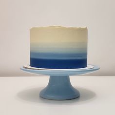 a blue and white ombrella cake sitting on top of a plate next to a wall