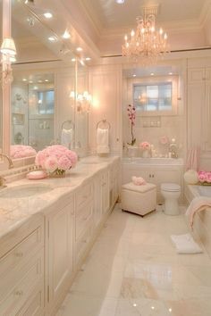 a white bathroom with chandeliers and pink flowers