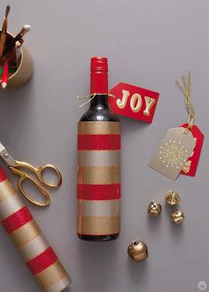 a bottle of wine and some christmas decorations on a table next to a pair of scissors