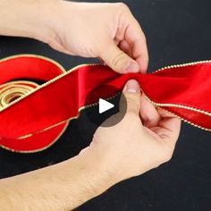 a person is tying a red ribbon on top of a guitar with gold trimmings