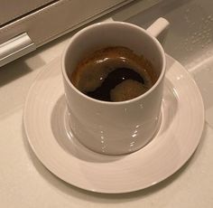 a cup of coffee sitting on top of a white saucer