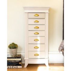 a white chest of drawers sitting next to a plant