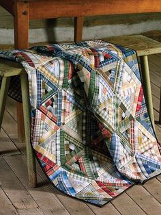 a table and bench with a quilt draped over it on the floor in front of them