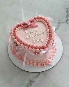 a pink heart shaped cake on top of a table