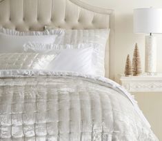 a bed with white comforter and pillows in a bedroom next to a night stand