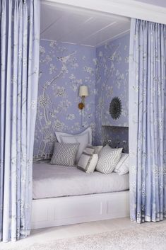 a bedroom with blue and white wallpaper and curtains