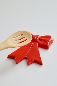 a wooden spoon with a red bow on it and a plastic spatula in the shape of a christmas tree