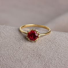 a close up of a ring with a red stone in it on a gray surface