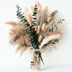 dried flowers are arranged in a vase on a white background