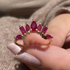 a close up of a person holding a ring with red stones