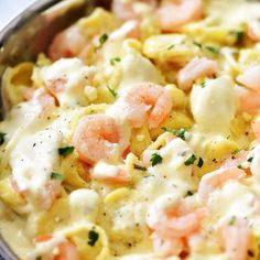 a bowl filled with pasta and shrimp covered in cheese sauce, garnished with parsley