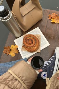 someone is sitting at a table with their feet on the table and holding a coffee cup