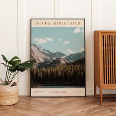 the rocky mountains poster is next to a wooden chair and potted plant in front of it