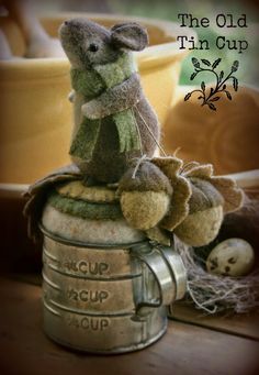 a teddy bear sitting on top of an old tin cup