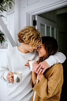 two people standing next to each other holding coffee cups