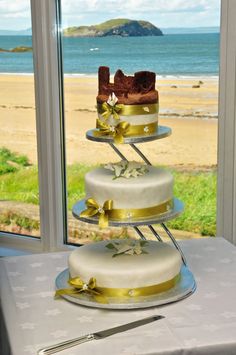 a three tiered cake sitting on top of a table next to a large window