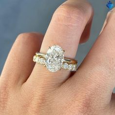 a woman's hand with a diamond ring on top of her finger and the other hand holding an engagement ring