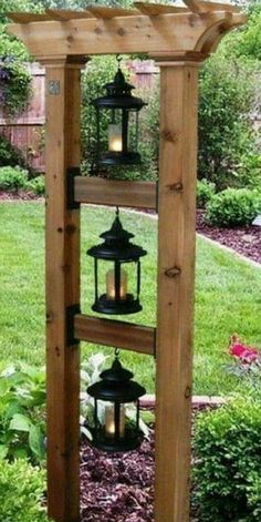 a wooden structure with lanterns hanging from it's sides in the middle of a garden