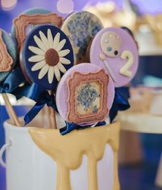 some cookies are in a vase with blue ribbons on it and decorated like flowers,